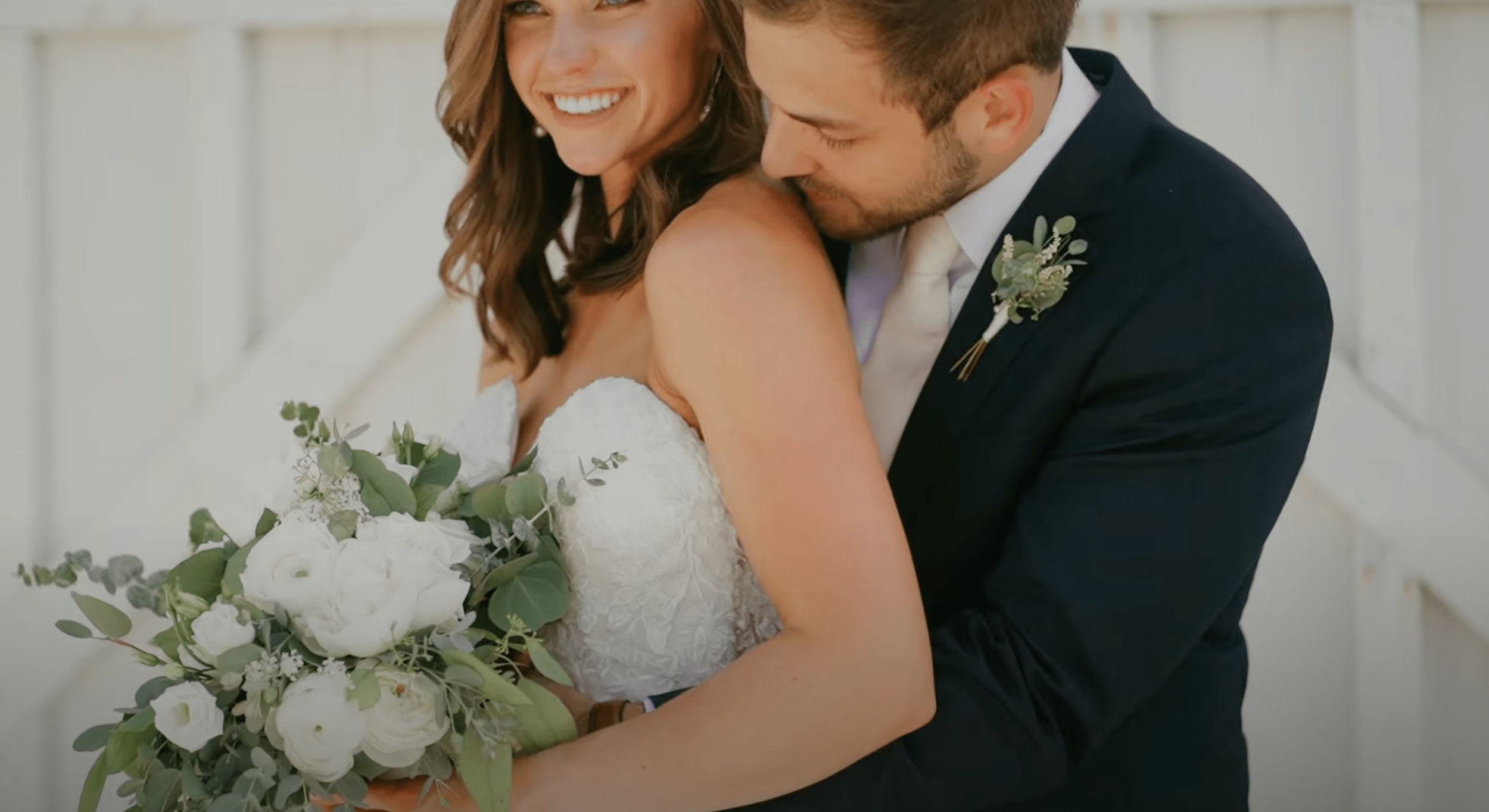 groom embraces bride as she holds bouquet