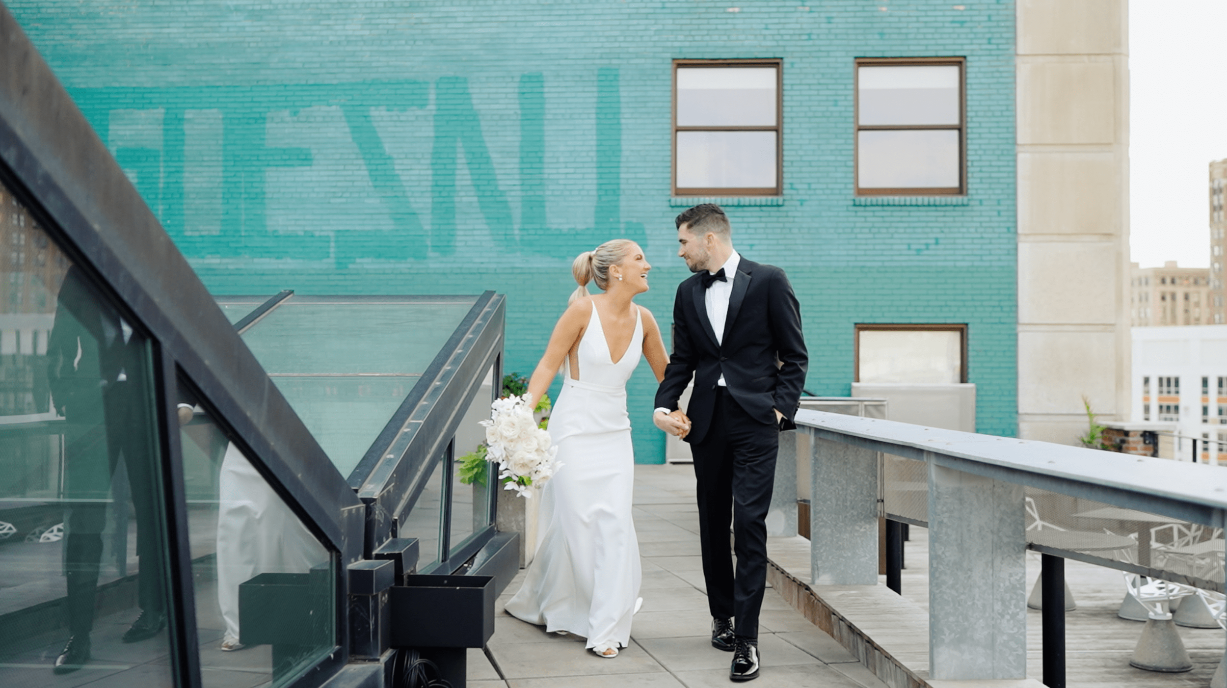 bride and groom hold hands and walk along the rooftop of the madison in detroit michigan